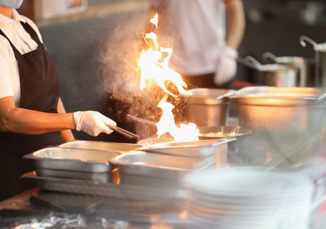 A chef cooks a dish over an open flame.